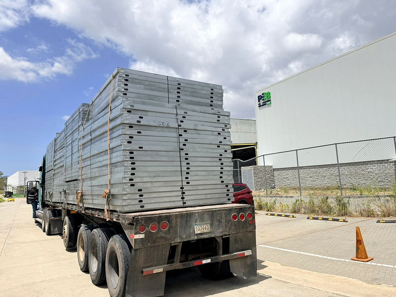 Camión de plataforma cargado con paneles perforados de acero liviano saliendo de la planta de fabricación en Panamá