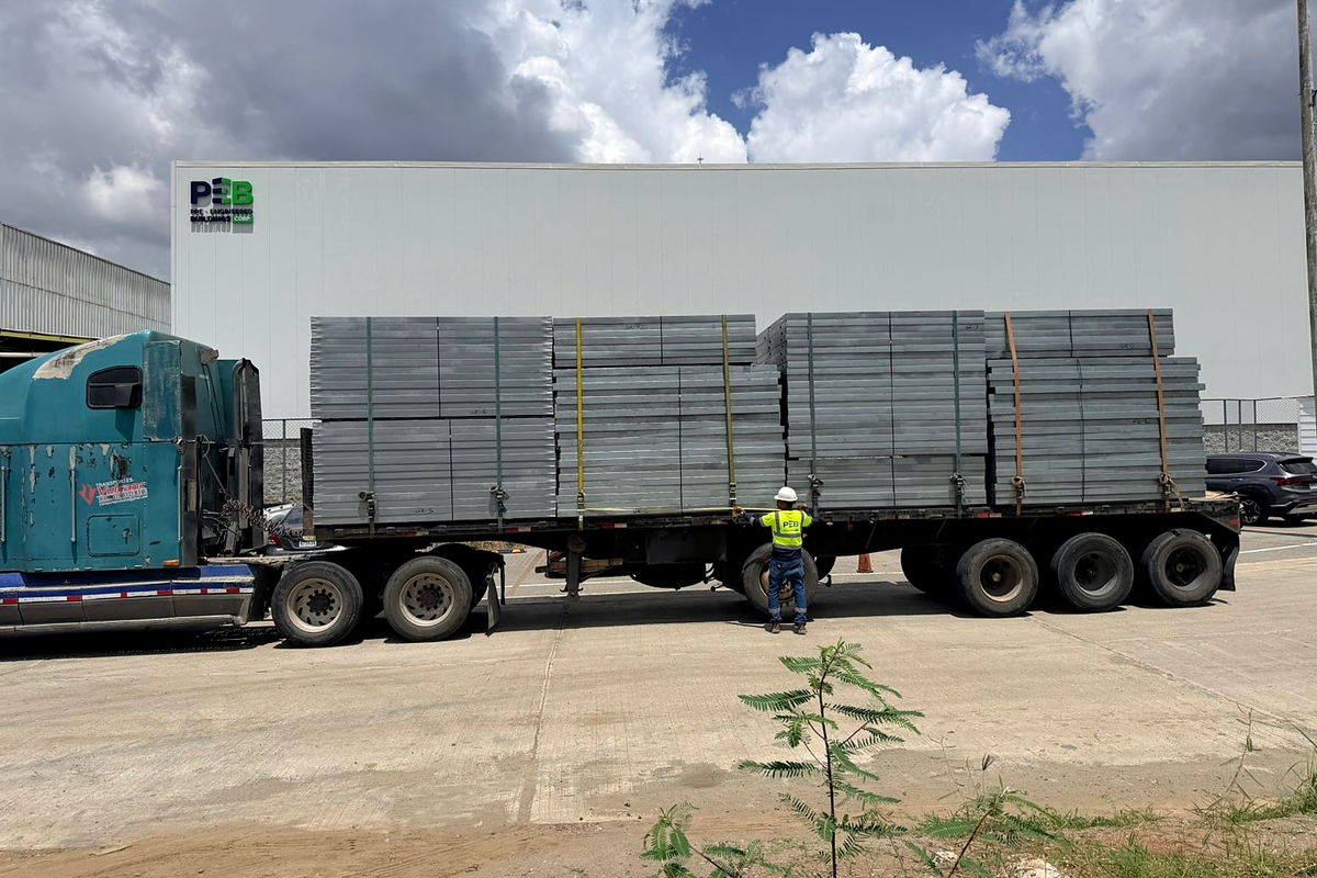 Camión de plataforma cargado y trincado con paneles estructurales de acero liviano, listo para salir de la planta de NewCon Steel en Panamá
