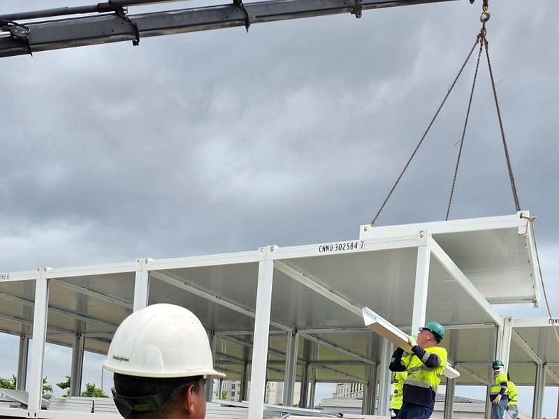 Izaje con grúa de un módulo estructural de acero liviano durante el montaje en obra, sobre pedestales de concreto