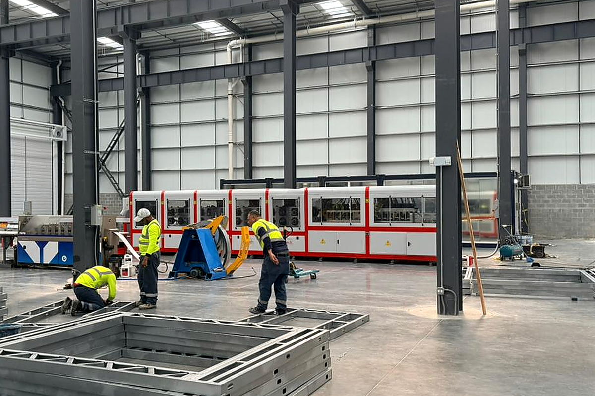 Línea de perfilado (rolado en frío) y desenrollador de bobina en la nave de producción de NewCon Steel, con operarios armando marcos estructurales