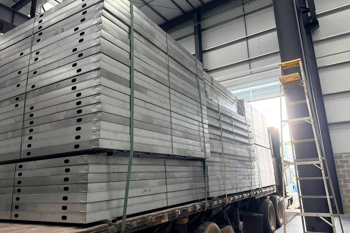 Paneles estructurales preensamblados de acero liviano, con perforaciones de paso para instalaciones, estibados sobre plataforma en la planta