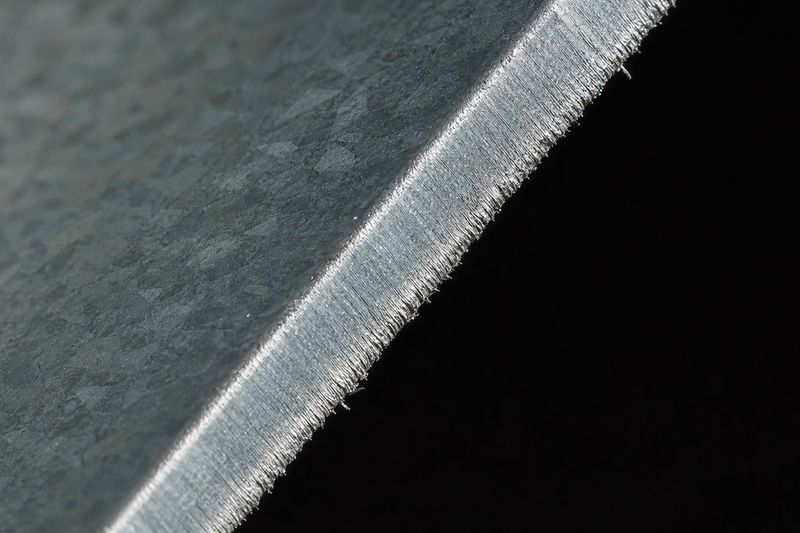 Macro del canto cortado de una lámina de acero con recubrimiento Zn-Al-Mg, con el acero desnudo del corte y la escarcha del recubrimiento