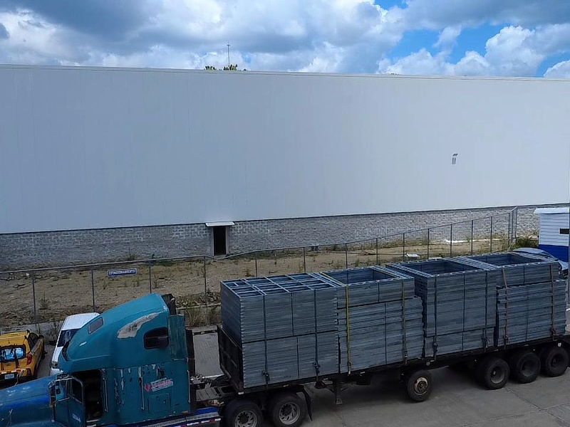 Vista aérea de la planta de fabricación en Panamá con un camión cargado de marcos estructurales de acero liviano en el patio de despacho